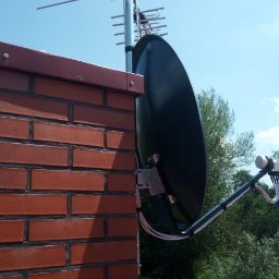 Woj-Bol Technology Wojciech Ból - Antena satelitarna i antena naziemna zamontowane na kominie z czerwonej cegły, widok na błękitne niebo i zieleń ogrodu.