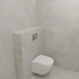 Minimalistyczna łazienka: podwieszana miska WC z szarymi płytkami imitującymi kamień, ukryty system spłukiwania. Nowoczesny design, czyste linie.