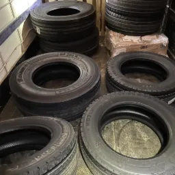 Stos opon Continental i Barum różnych rozmiarów, widoczny w przestrzeni ładunkowej busa, przygotowanych do transportu.