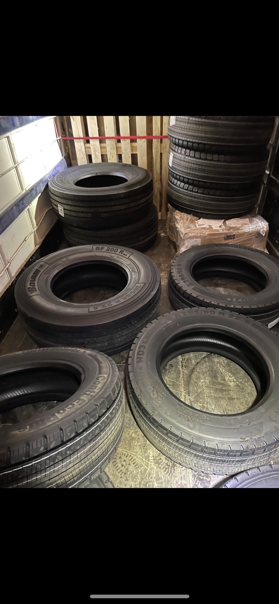 Stos opon Continental i Barum różnych rozmiarów, widoczny w przestrzeni ładunkowej busa, przygotowanych do transportu.