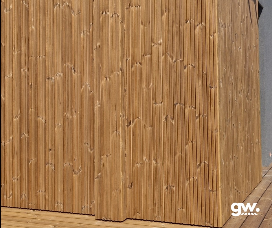 Fragment elewacji i tarasu wykonanych z deski thermososna, widoczne pionowe ułożenie desek elewacyjnych i poziome deski tarasowe.