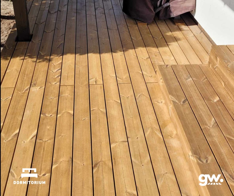 Jasny taras z desek, fragment zadaszenia i schodki, widok z góry, naturalne usłojenie drewna.