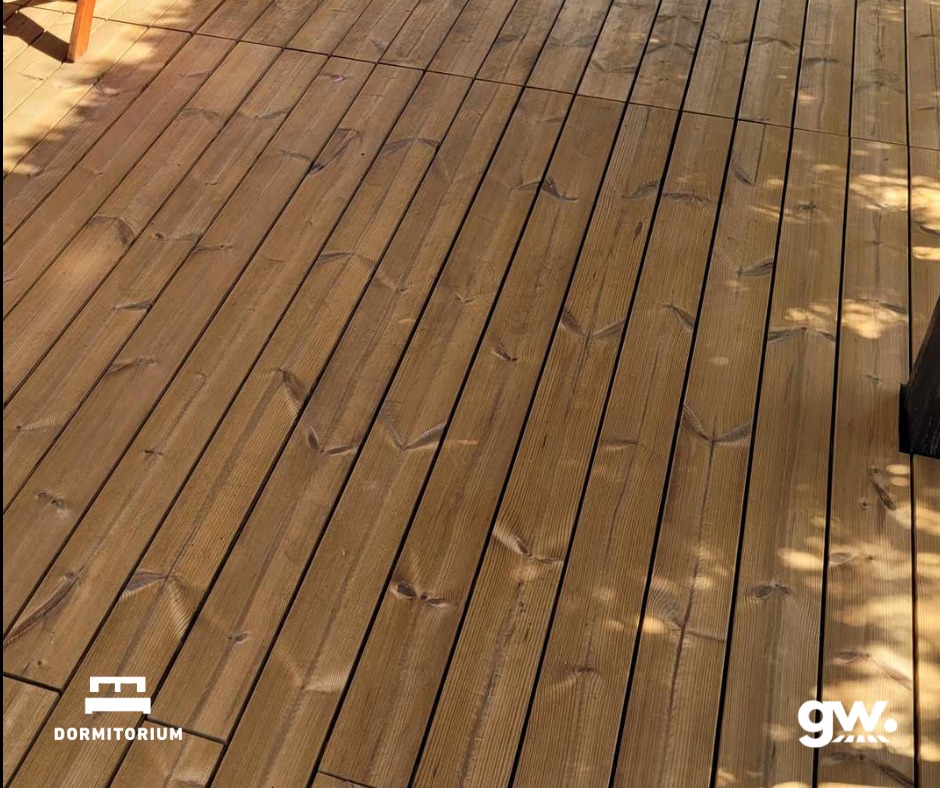 Ułożony taras z deski thermososna, widoczne naturalne usłojenie drewna i cień drzewa padający na powierzchnię.