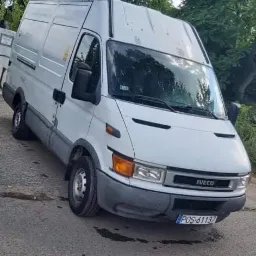 Biały samochód dostawczy marki Iveco zaparkowany na ulicy, widoczny z przodu i boku, z numerem rejestracyjnym POS 61137.