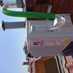 Coldhome - Zamontowana jednostka zewnętrzna klimatyzatora marki Gree na dachu budynku z widocznym zielonym przewodem wentylacyjnym i elementami instalacji odprowadzającej powietrze.