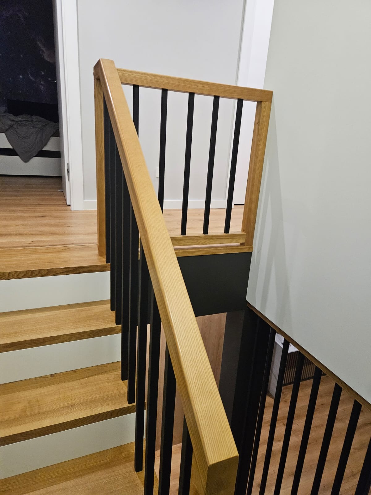 Nowoczesne schody z jasnego drewna z czarnymi balustradami, widok z góry. Minimalistyczny design.