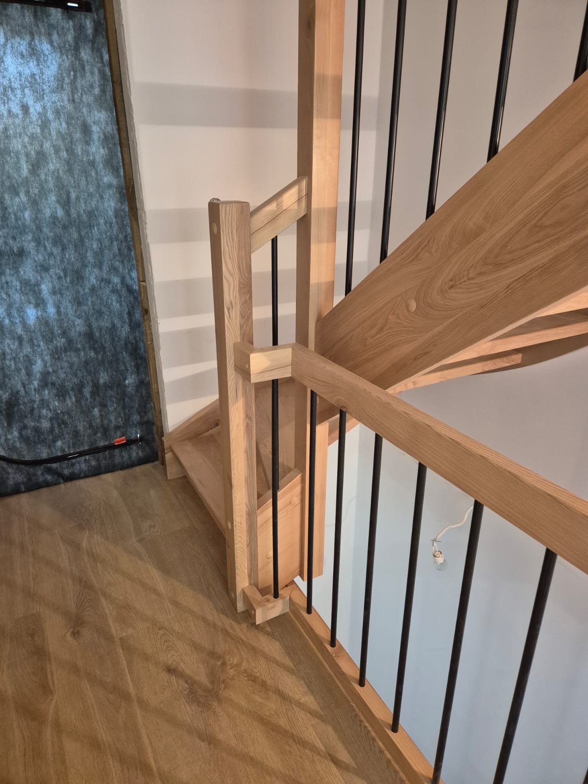 Jasne stopnie z drewna i czarne, metalowe balustrady, widok z góry. Minimalistyczny design, naturalne materiały, drewniana podłoga.