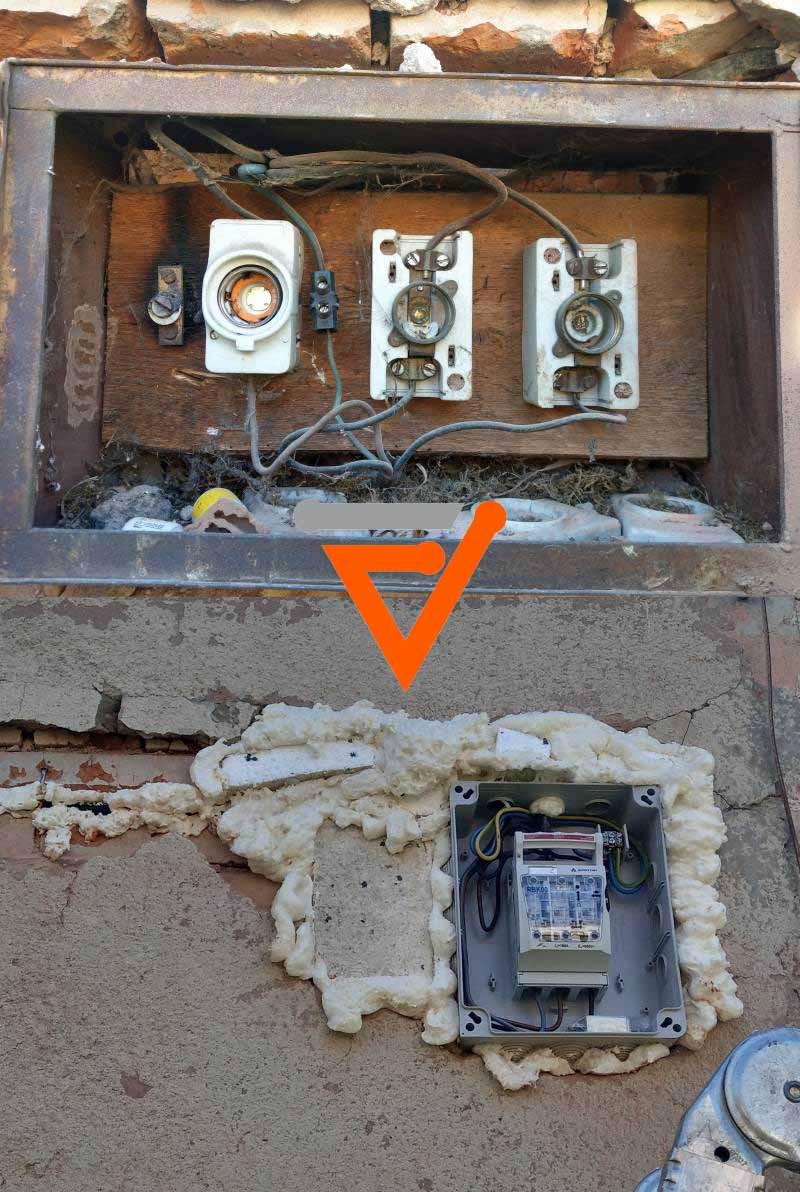 Stara skrzynka z bezpiecznikami topikowymi i nowa skrzynka z zabezpieczeniami różnicowoprądowymi, zabezpieczona pianką montażową, na tle ceglanej ściany.