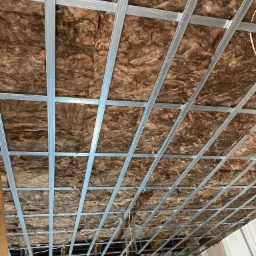 Poddasze z widoczną izolacją z wełny mineralnej, zabezpieczoną metalowym stelażem kratowym, przygotowane do montażu płyt gipsowo-kartonowych.