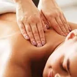 Dłonie masujące plecy kobiety leżącej na białym ręczniku, widoczne lekkie zaczerwienienie skóry.