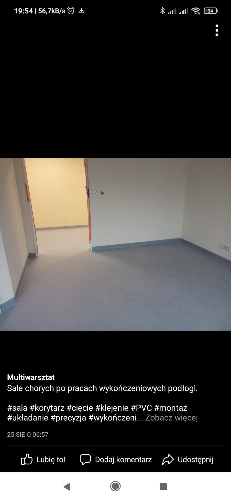 Szare, jednolite wykończenie podłogi z listwami przypodłogowymi w jasnym pomieszczeniu, widoczne fragmenty innych pomieszczeń przez otwarte drzwi.