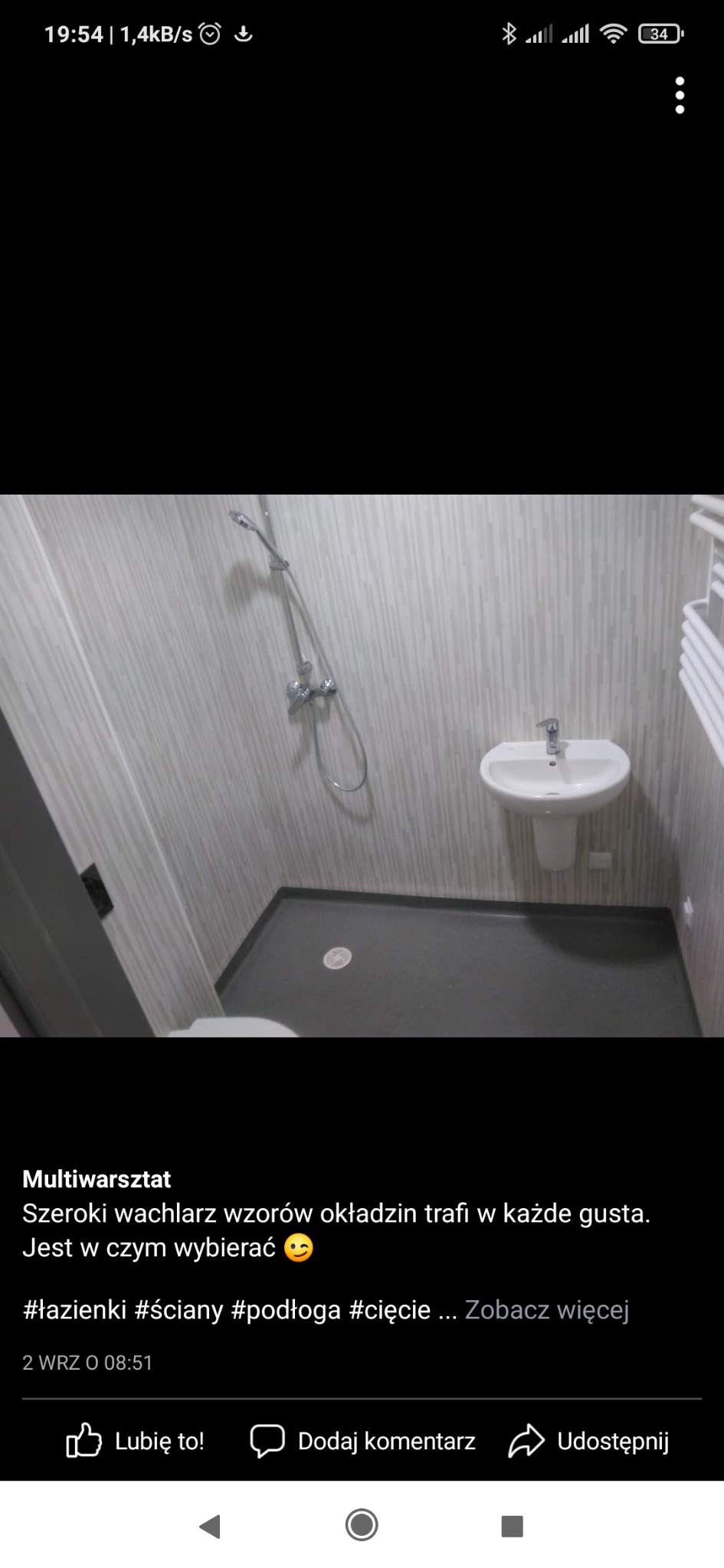 Nowoczesna łazienka po remoncie z szarymi panelami ściennymi imitującymi drewno, białą umywalką na postumencie, szarą podłogą i chromowaną armaturą.