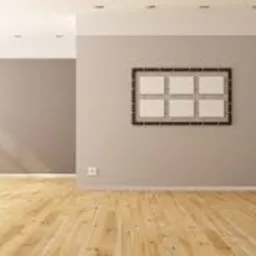Puste, jasne pomieszczenie z drewnianą podłogą, pomalowanymi na szaro ścianami i białym sufitem z punktowym oświetleniem. Na ścianie wisi dekoracja składająca się z sześciu kwadratowych ramek.