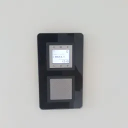 Ścienny panel sterowania inteligentnego domu, wyświetlający stację radiową ESKA, zamontowany na białej ścianie.