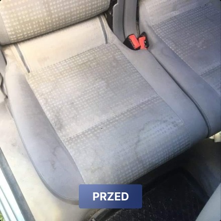 Tapicerka samochodowa z wyraźnymi plamami i zabrudzeniami, widoczne pasy bezpieczeństwa, zdjęcie typu 'przed' czyszczeniem.