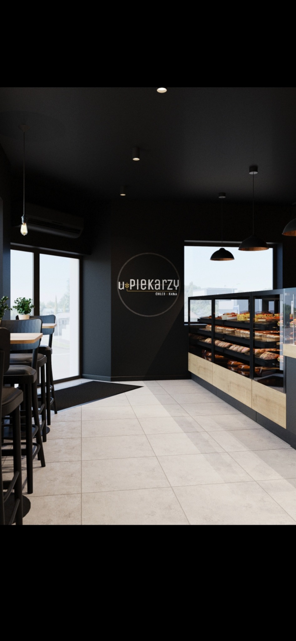 Wnętrze piekarni w czerni i bieli z jasną podłogą. Widoczne stoliki barowe, witryna z pieczywem i logo piekarni na ścianie. Minimalistyczny design.