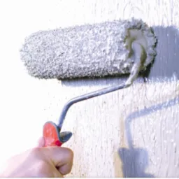 Nakładanie struktury wałkiem na ścianę w Tarnowie, widoczny wałek z szorstką fakturą i ręka wykonawcy.