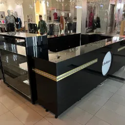 Czarna wyspa handlowa z logo Orvella w centrum handlowym, z przeszkloną witryną i złotymi akcentami. Widoczny fragment chodnika i manekiny w tle.