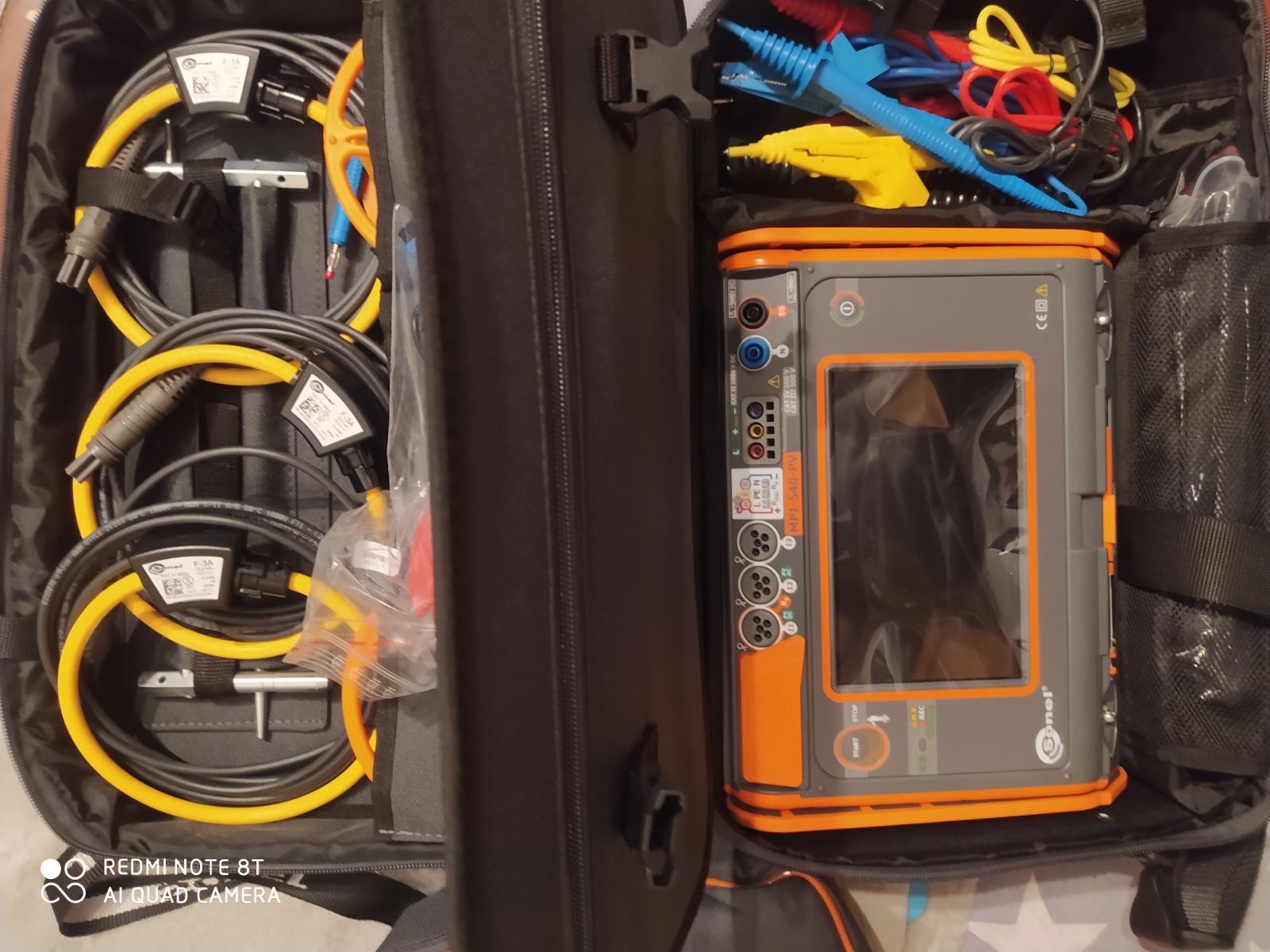 Otwarta torba narzędziowa z miernikiem elektrycznym Sonel MPL-540-PV, przewodami pomiarowymi z cęgami, sondami i innymi akcesoriami do pomiarów elektrycznych.