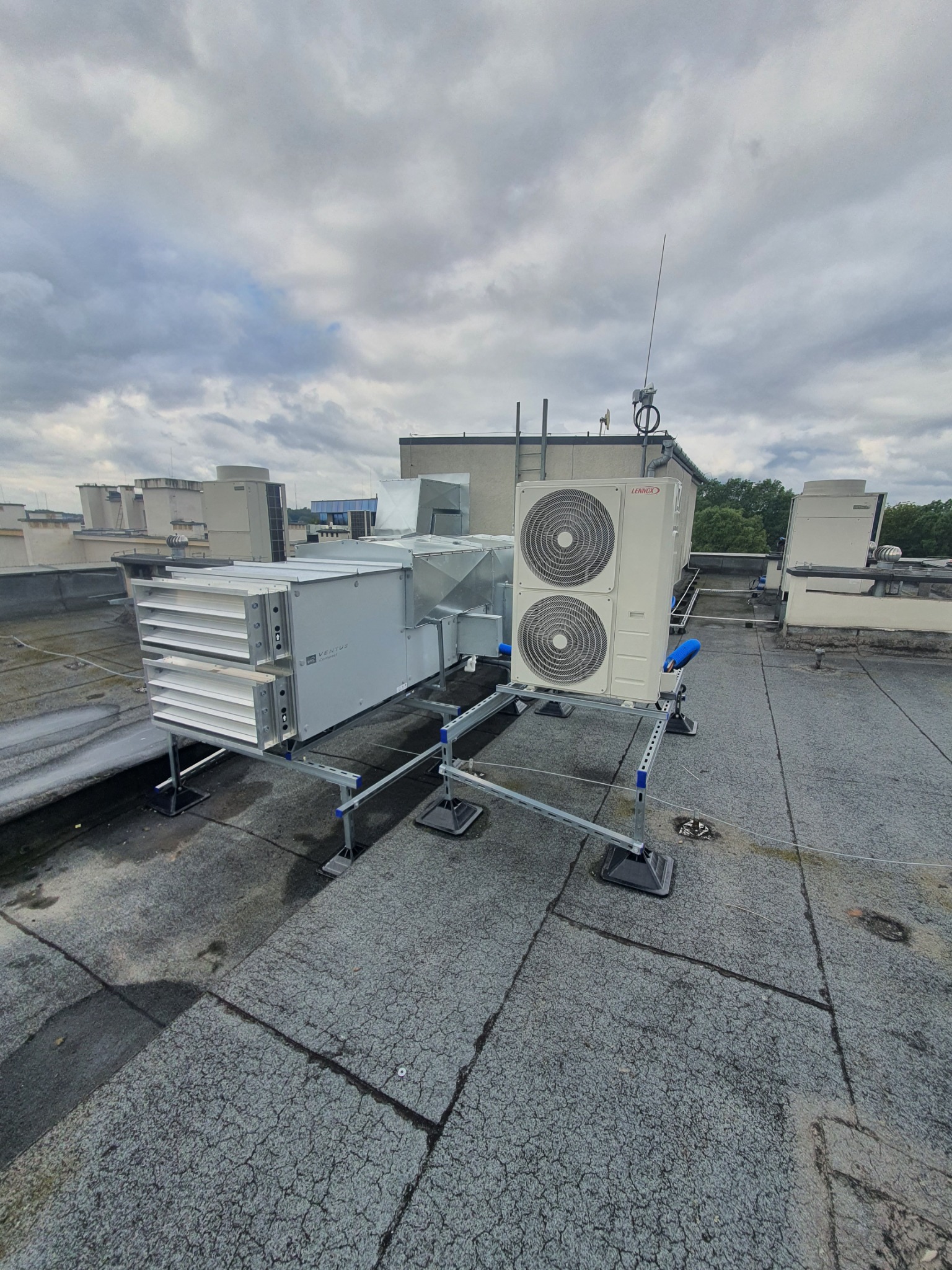 Instalacja wentylacyjna i klimatyzacyjna na dachu budynku komercyjnego, widoczne elementy centrali wentylacyjnej Ventus Compact oraz jednostki zewnętrznej klimatyzacji Lennox, zamontowane...