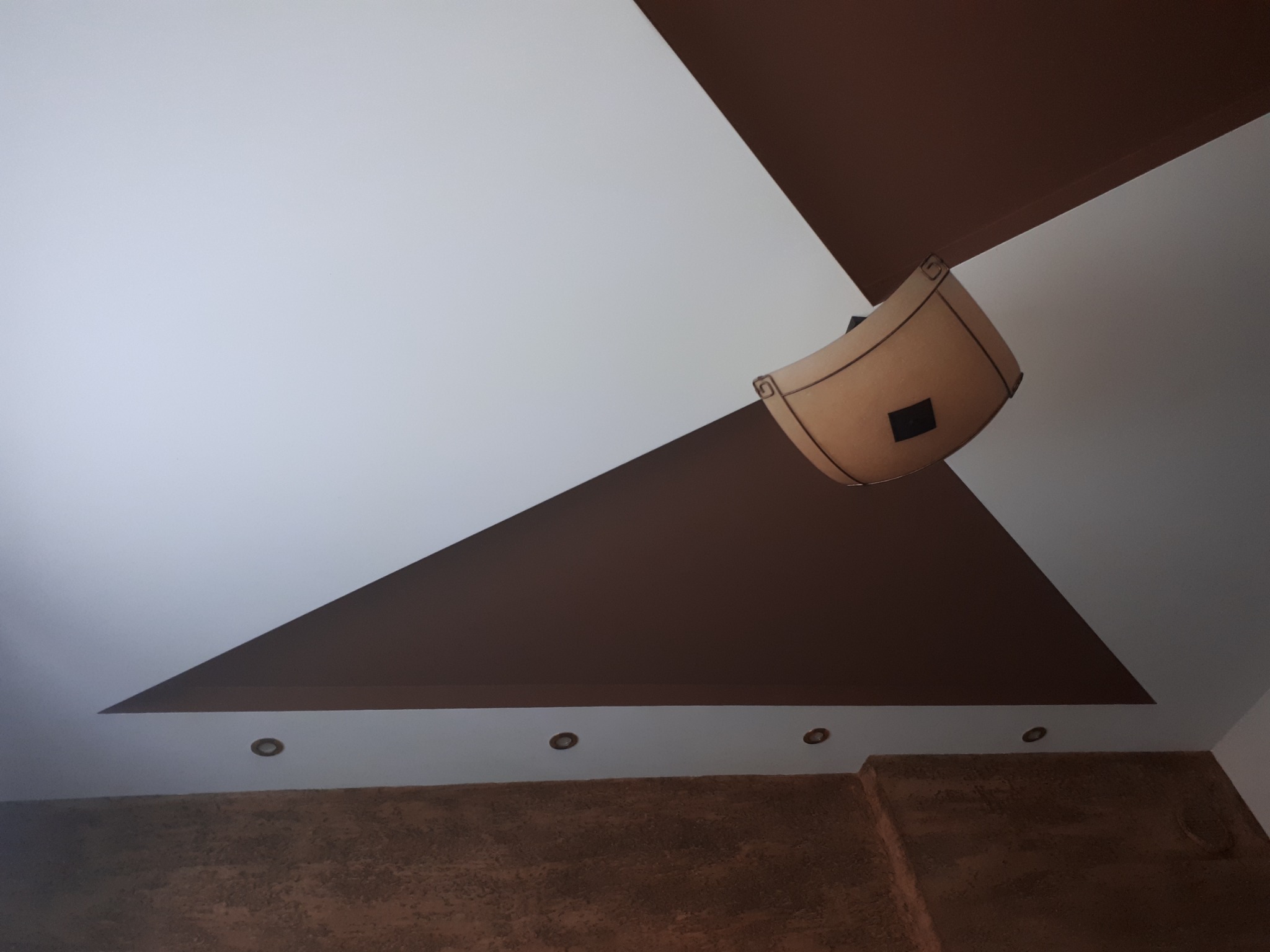 Wielopoziomowy sufit w odcieniach bieli i brązu z oświetleniem punktowym i lampą w stylu retro.