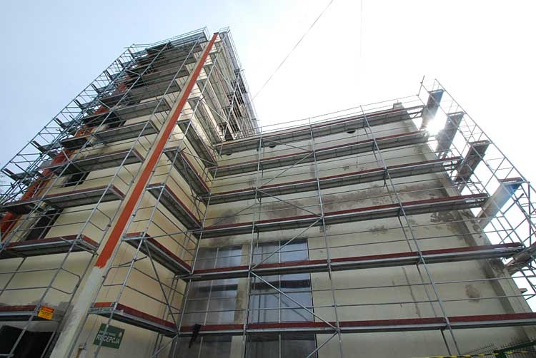 Budynek w Pabianicach w trakcie renowacji elewacji, otoczony rusztowaniami, widok z dołu.