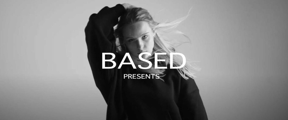 Czarno-białe zdjęcie kobiety z rozwianymi włosami w ciemnej bluzie, z napisem 'BASED PRESENTS' na pierwszym planie.
