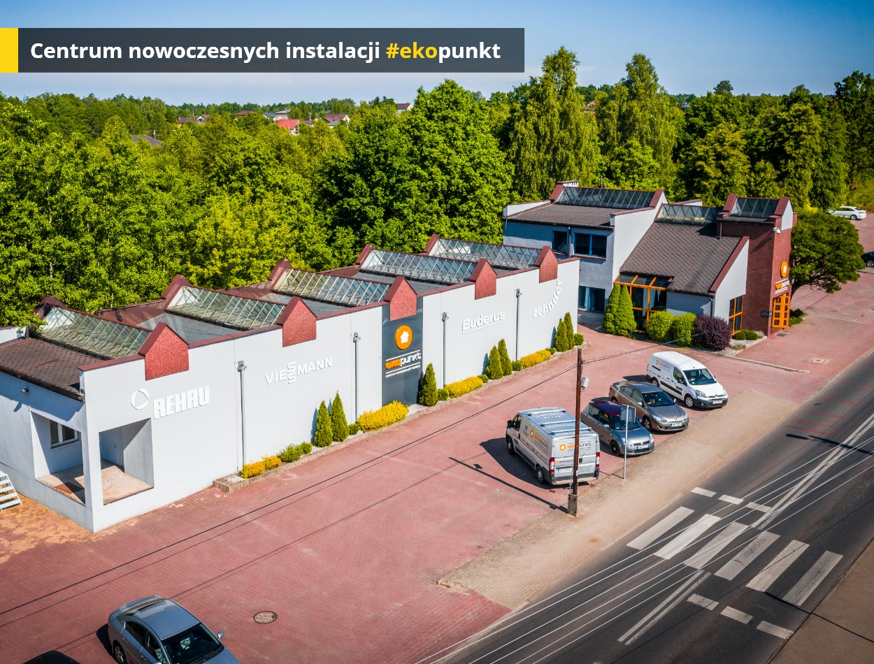 Budynek centrum nowoczesnych instalacji z logo firm Rehau, Viessmann, Buderus, z zaparkowanymi samochodami, widok z góry.