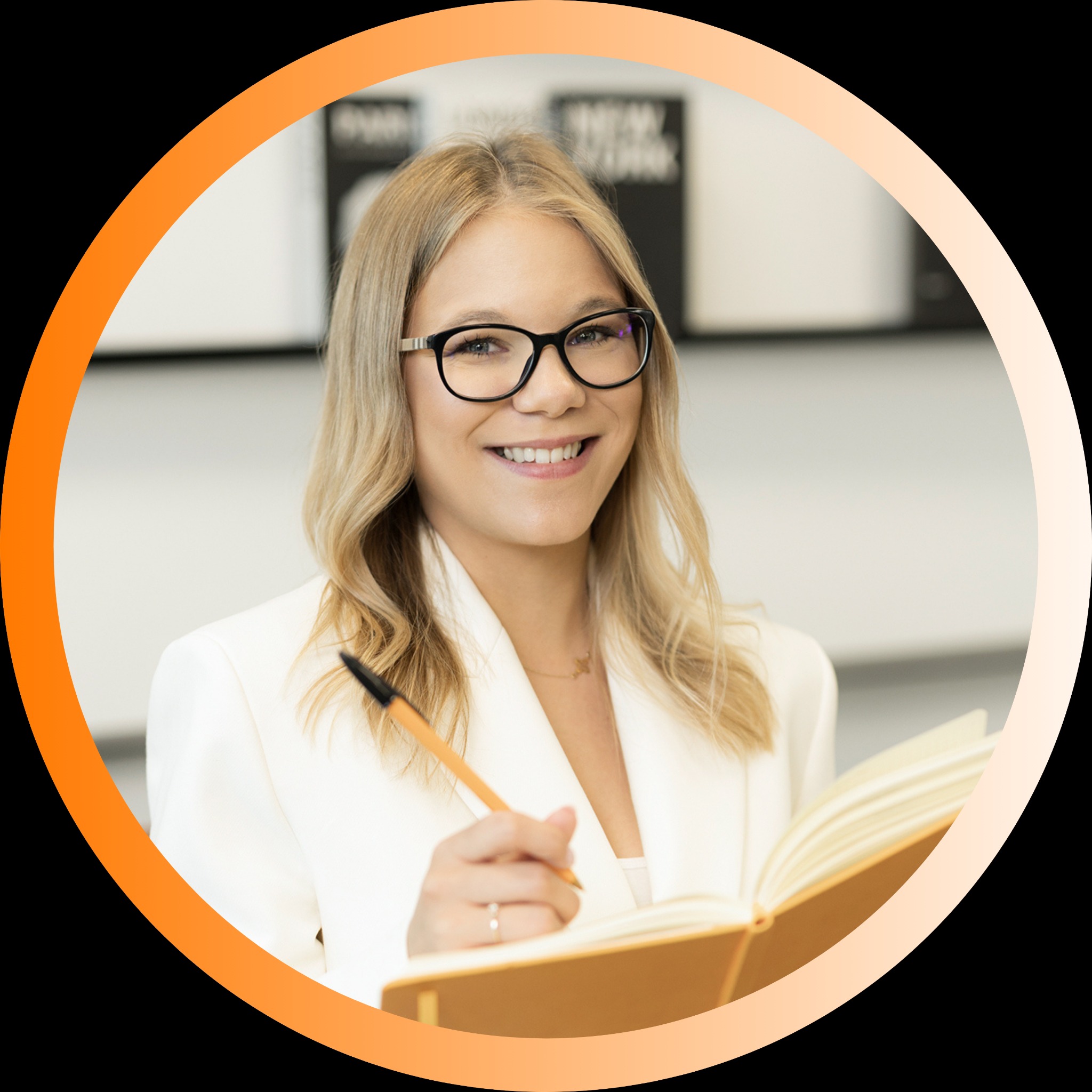 Uśmiechnięta blondynka w okularach i białym żakiecie pisze w notatniku. W tle białe półki z książkami. Profesjonalny wizerunek doradcy finansowego.