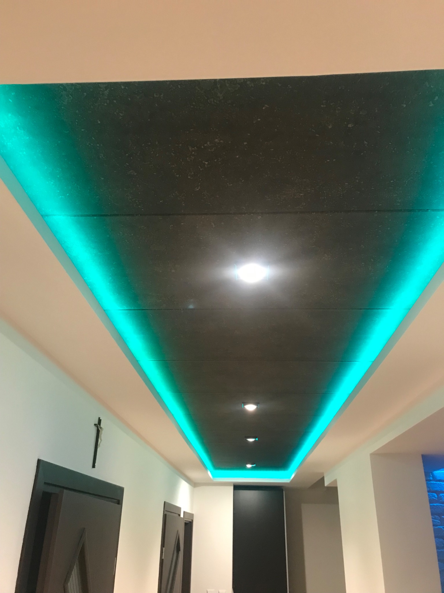 Nowoczesny sufit podwieszany z szarą fakturą i podświetleniem LED w kolorze turkusowym, widok z dołu.