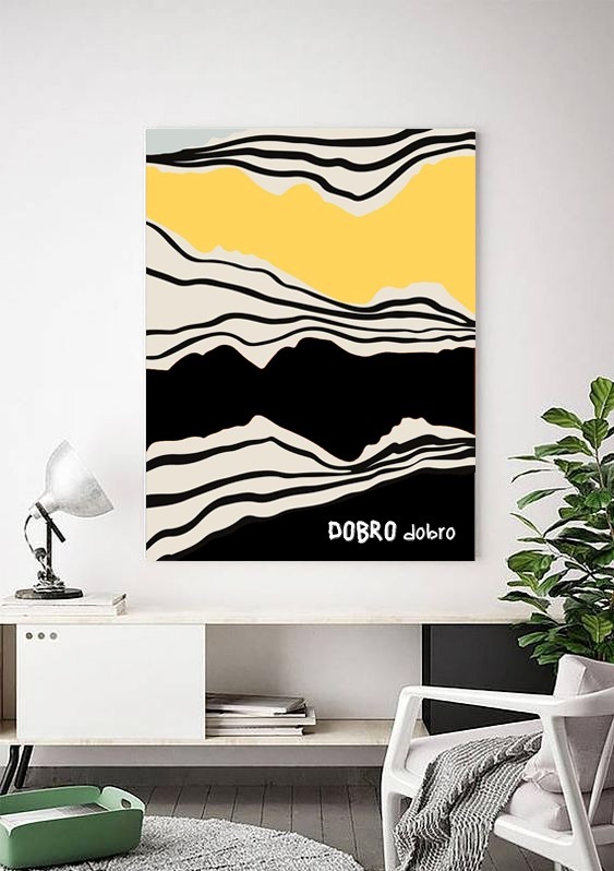 Abstrakcyjny obraz z żółto-czarnym motywem górskim i napisem 'DOBRO dobro' w minimalistycznym wnętrzu z białą komodą, lampką i rośliną doniczkową.
