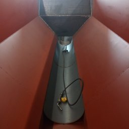 Adeko System Janusz Dźwigoń - Wnętrze konstrukcji stalowej w kształcie stożka, widok z góry, z widocznym uchwytem spawalniczym na dnie, sugerujące etap spawania lub kontroli po spawaniu.