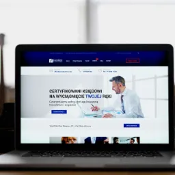 Ekran laptopa wyświetlający stronę internetową biura księgowego Sussex Business z hasłem 'Certyfikowani księgowi na wyciągnięcie Twojej ręki', obok leżą dwa aparaty fotograficzne.