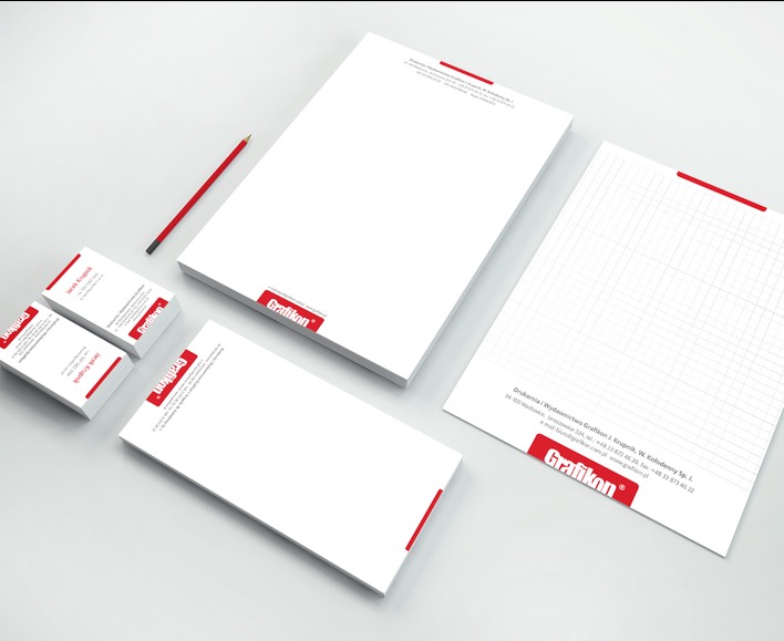 Zestaw materiałów biurowych z logo firmy Grafikon: wizytówki, papier firmowy z liniaturą i bez, oraz ołówek, ułożone na jasnym tle.