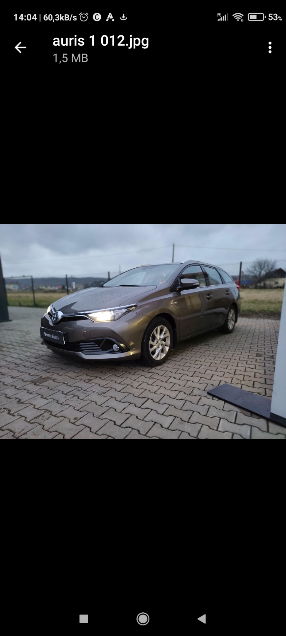 Brązowy samochód osobowy typu kombi, Toyota Auris, zaparkowany na brukowanej powierzchni we Wrocławiu, z widocznym logo 'Pewne Auto' na przednim zderzaku.