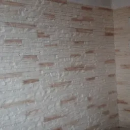 Wykończona ściana z dekoracyjnej, jasnej cegły imitującej kamień, z widocznym narożnikiem i jasną fugą, tworząca efekt tr&oacute;jwymiarowości.