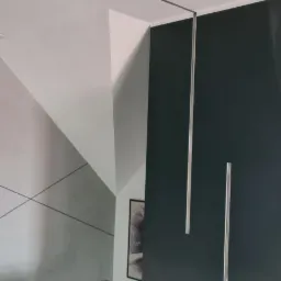 Nowoczesne wnętrze z ciemną ścianą, minimalistycznymi listwami sufitowymi i schodami z białą balustradą.