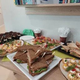 Stół z różnorodnymi przekąskami w Jeleniej Górze: kanapki z ciemnego pieczywa, tartaletki z kremem i warzywami, mini kanapeczki z szynką parmeńską, oraz brownie na deser.