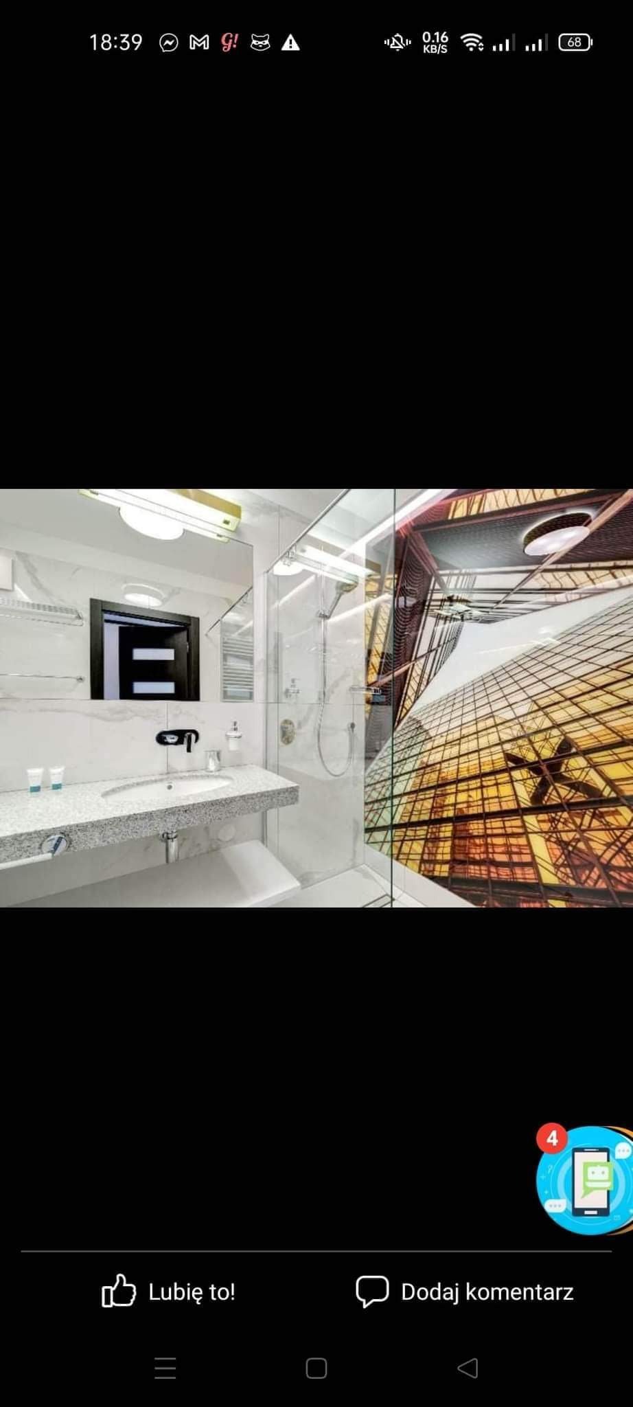 Nowoczesna łazienka z kabiną prysznicową ze szklaną ścianą, marmurową umywalką i fototapetą przedstawiającą drapacz chmur.