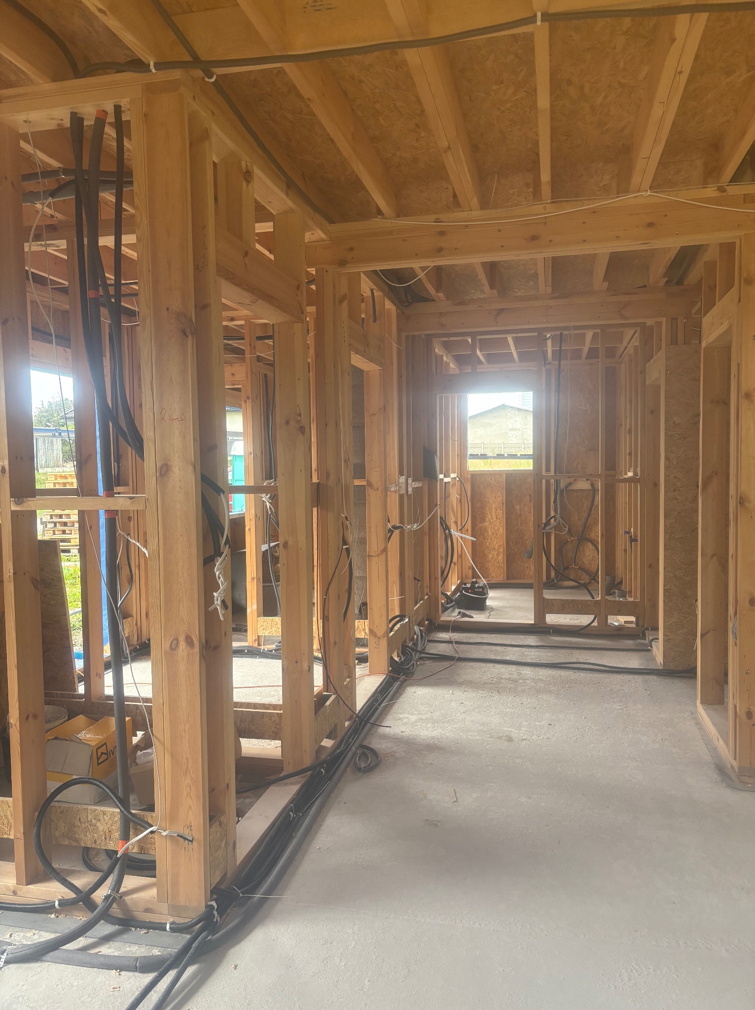 Wnętrze w surowym stanie, konstrukcja szkieletowa z drewna, widoczne instalacje elektryczne i sanitarne. Stan deweloperski, przygotowanie do dalszych prac wykończeniowych.