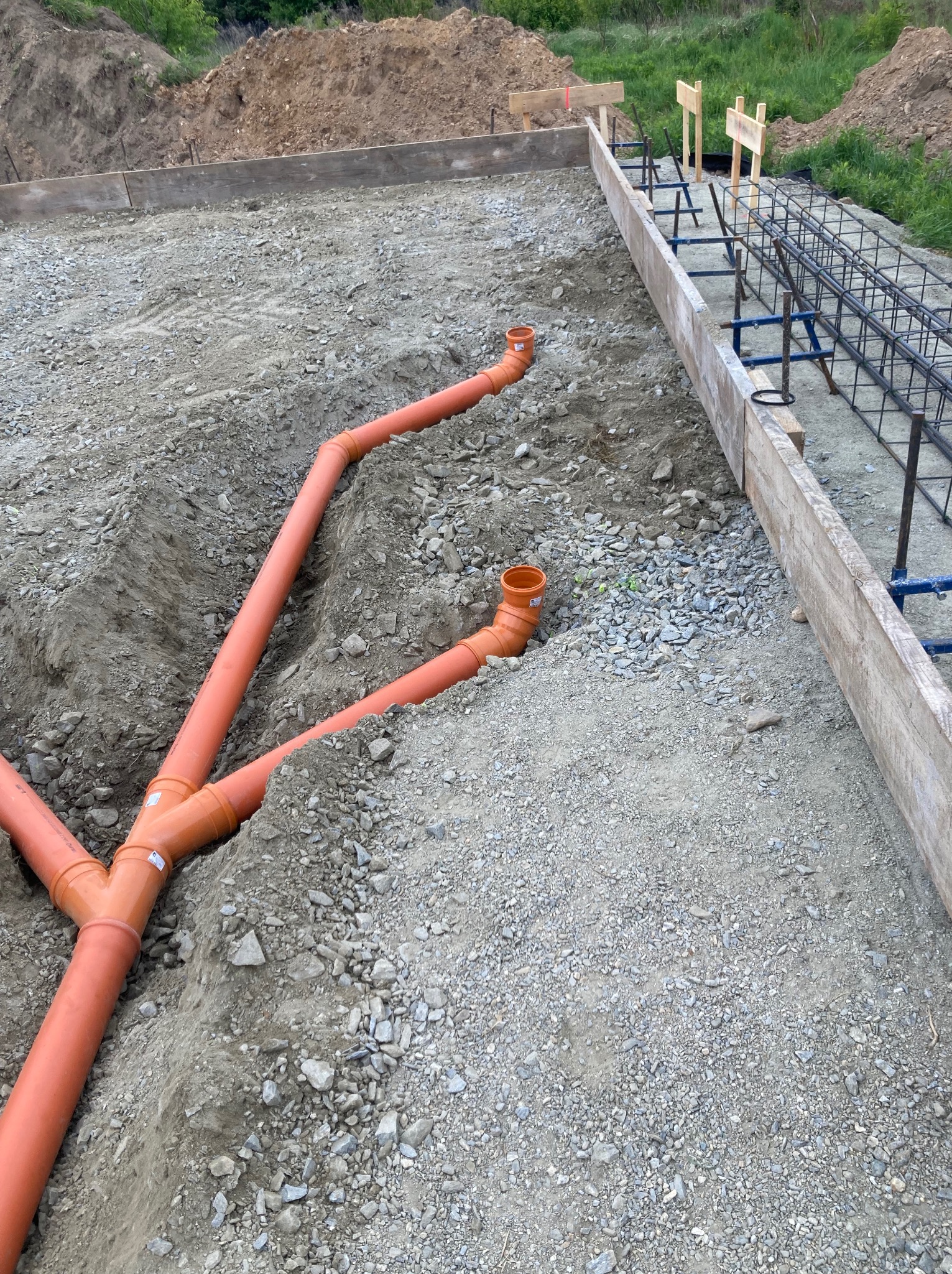 Fundament pod dom szkieletowy z widocznymi rurami kanalizacyjnymi i zbrojeniem. Deskowanie wzdłuż krawędzi. Etap budowy, widok z góry.