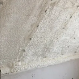 Poddasze po ociepleniu pianką PUR, widoczne metalowe elementy mocujące, ściana poniżej z widocznymi instalacjami elektrycznymi w stanie surowym.