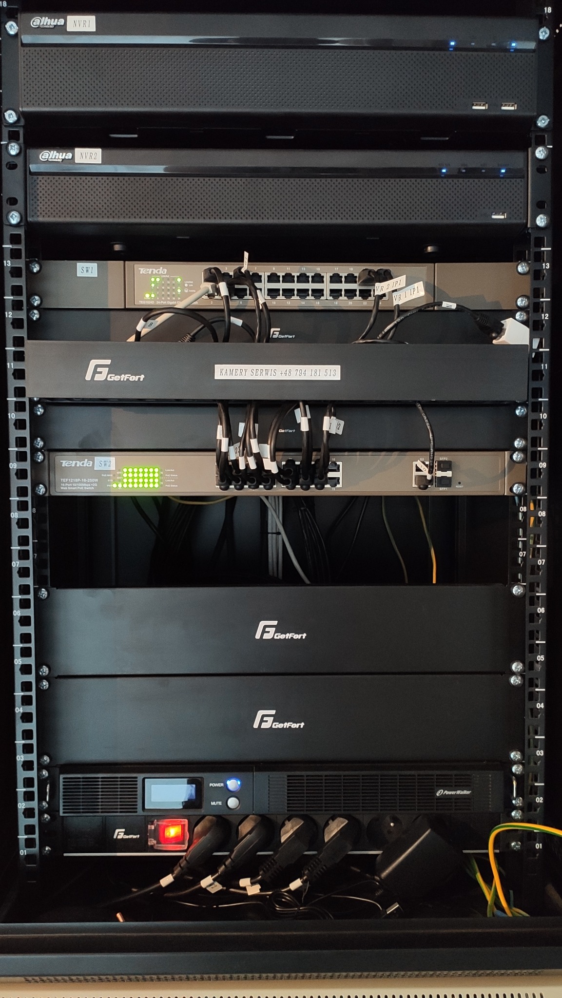 Szafa rack z zamontowanymi urządzeniami sieciowymi i rejestratorami Dahua NVR1 i NVR2, switchami Tenda, zasilaczem awaryjnym PowerWalker i urządzeniami GetFort, okablowanie, etykiety z opisami...