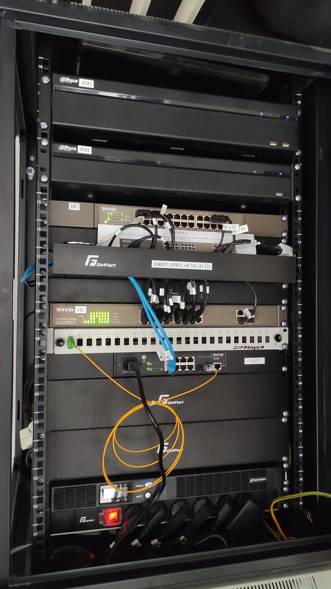 Szafa rack z urządzeniami sieciowymi i rejestratorami Dahua NVR1 i NVR2, switchami Tenda i GetFort, okablowaniem Ethernet i światłowodowym, zasilaczem awaryjnym Power Walker, w serwerowni.