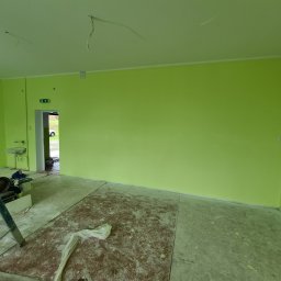 Od Nowa - Pomalowane na jasnozielono wnętrze z widocznymi narzędziami malarskimi, drabina i zabezpieczona podłoga przed malowaniem, widoczne niedociągnięcia w postaci wystających kabli i niezabezpieczonych...