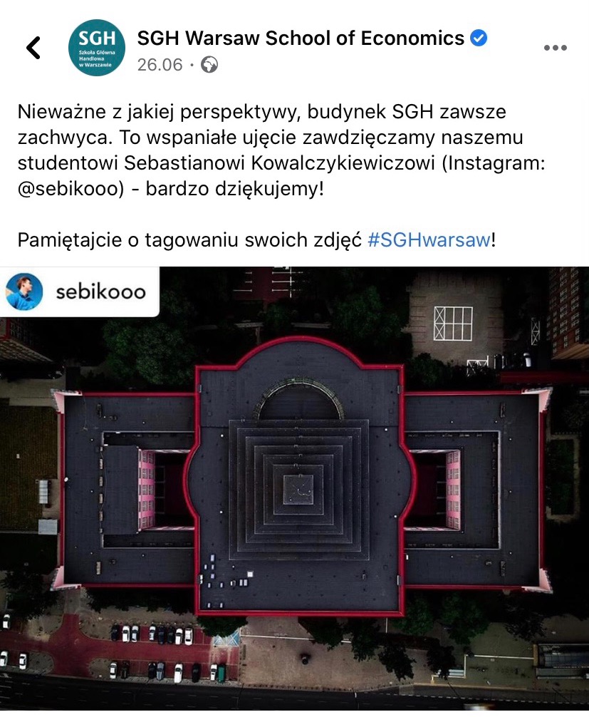 Widok z lotu ptaka na budynek Szkoły Głównej Handlowej w Warszawie, ukazujący charakterystyczną architekturę dachu z centralną, piramidalną strukturą i czerwonymi obwódkami.