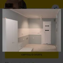 Jasnoszara kuchnia w trakcie aranżacji, widoczne białe szafki, płytki na ścianie do połowy wysokości, surowa podłoga, białe drzwi z czarnym paskiem, w tle logo firmy Fixly.