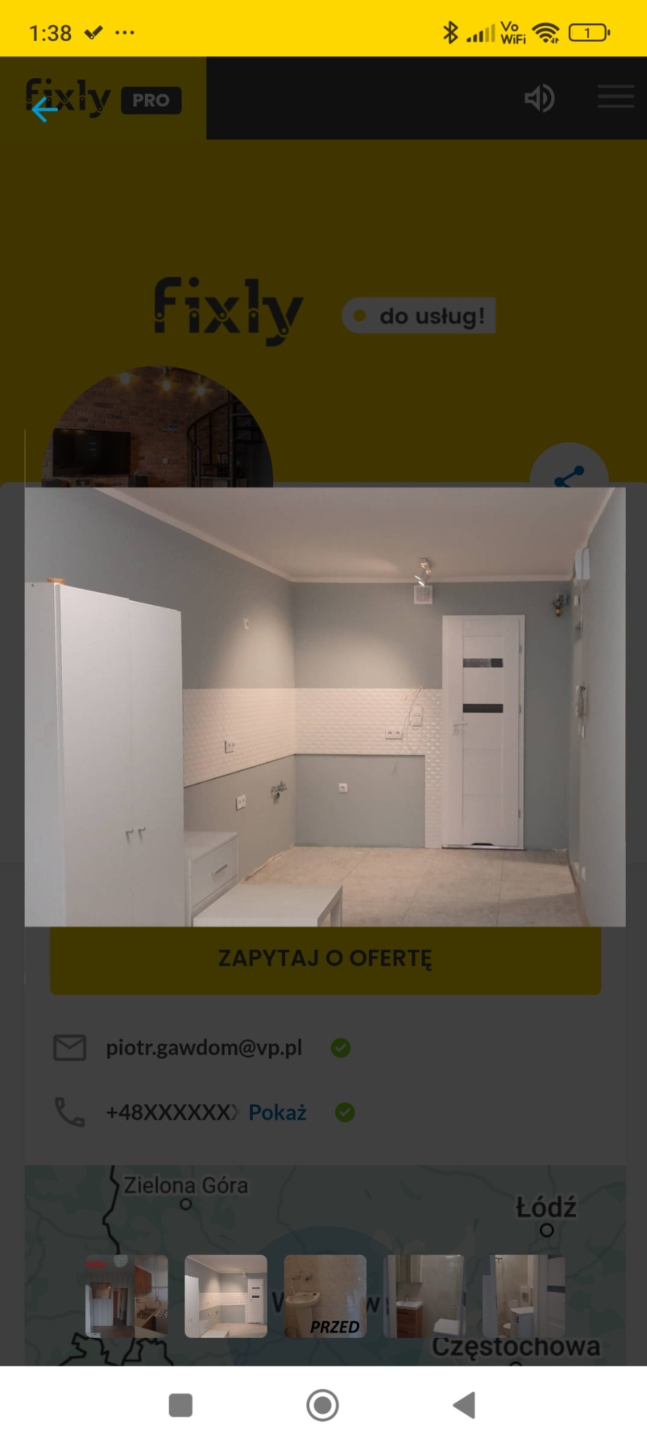 Jasnoszara kuchnia w trakcie aranżacji, widoczne białe szafki, płytki na ścianie do połowy wysokości, surowa podłoga, białe drzwi z czarnym paskiem, w tle logo firmy Fixly.