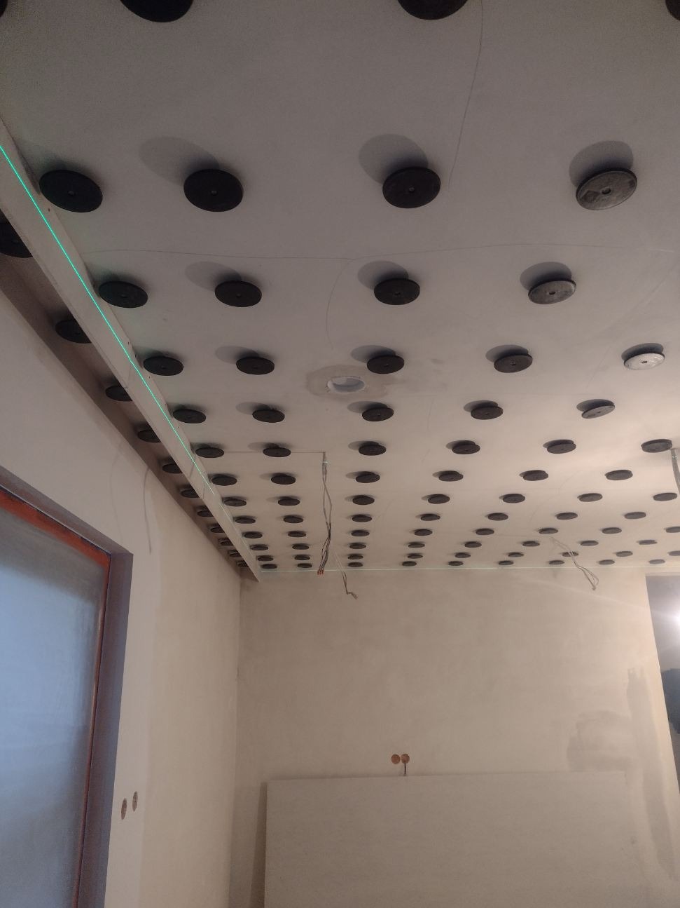 Montaż sufitu podwieszanego z płyt karton gips w Zawierciu, widoczne profile, płyty i punkty mocowania, a także poziomica laserowa.