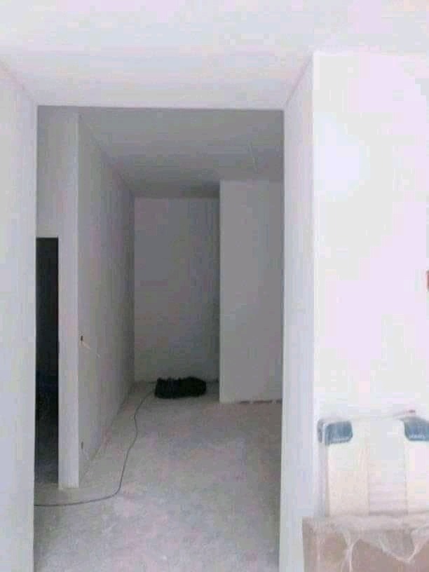 Wnętrze w trakcie prac wykończeniowych: ściany pokryte gładzią, widoczny kabel elektryczny na podłodze, przygotowane do malowania.